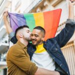 Deux hommes, dont l'un brandit un drapeau arc en ciel, s'embrassent